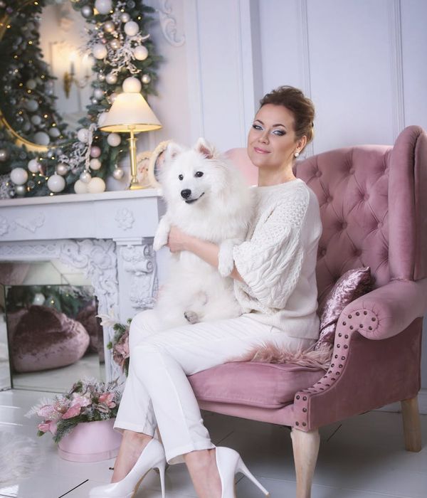 A woman performing a gentle yoga pose in a dark ambient studio with lavender light.